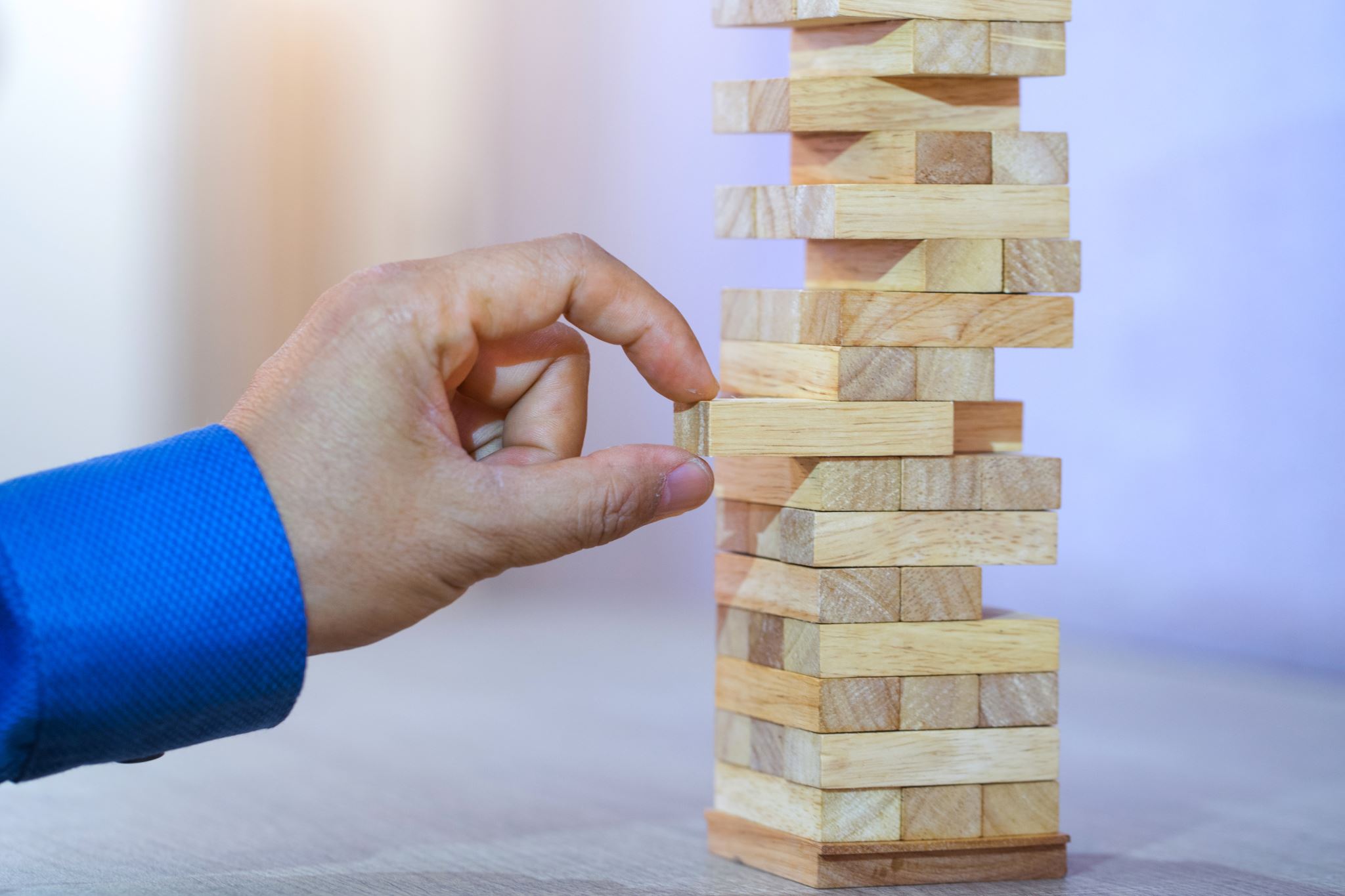 Business man pulling a block from Jenga tower